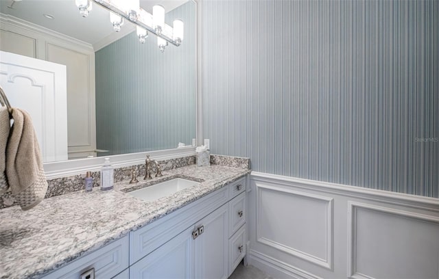 bathroom featuring a decorative wall, vanity, and an inviting chandelier