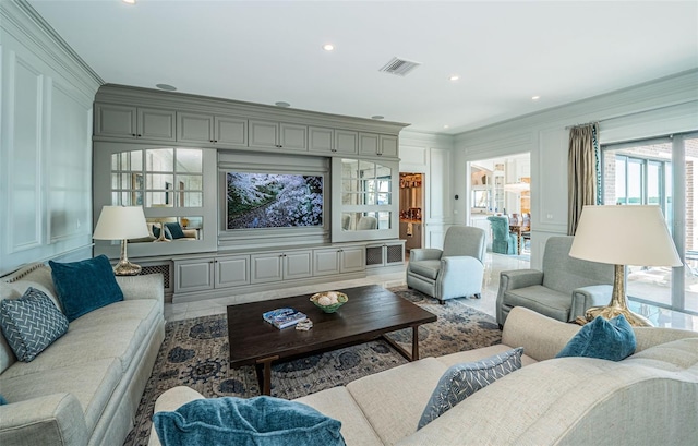 living area featuring recessed lighting, visible vents, a decorative wall, and ornamental molding