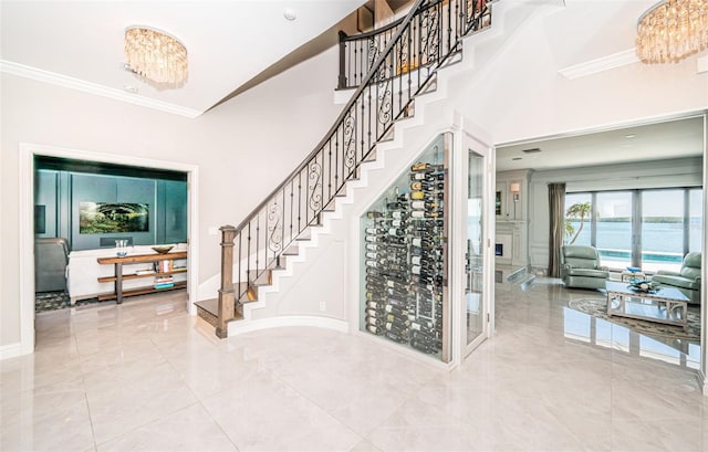 interior space with a towering ceiling, baseboards, stairs, ornamental molding, and an inviting chandelier