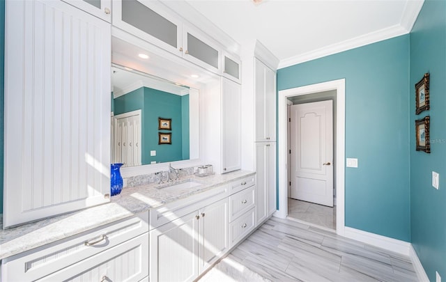 bathroom featuring baseboards, crown molding, and vanity