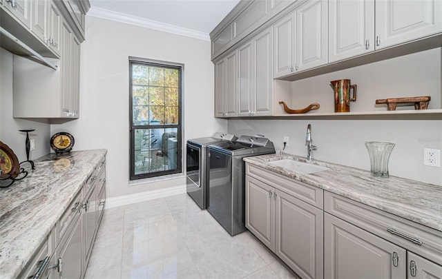 laundry area featuring cabinet space, ornamental molding, a sink, independent washer and dryer, and baseboards