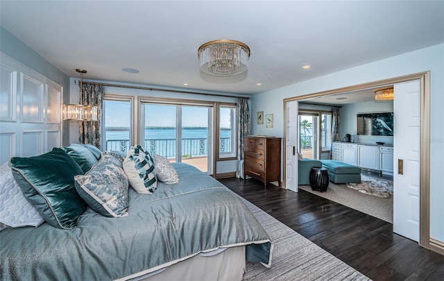 bedroom featuring dark wood-style floors, access to outside, a water view, and a notable chandelier