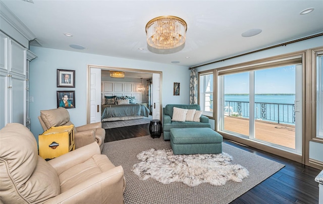 living room featuring recessed lighting, a water view, dark wood finished floors, and an inviting chandelier