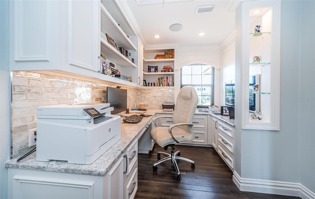 office space featuring dark wood-style flooring, visible vents, baseboards, built in desk, and crown molding