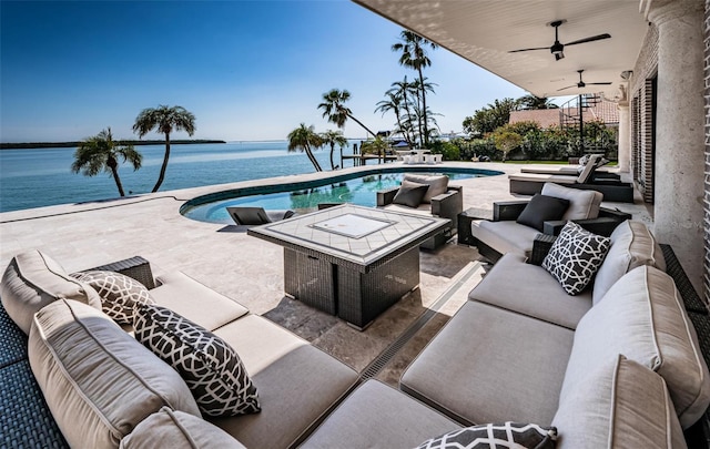 outdoor pool with ceiling fan, a patio area, a water view, and an outdoor living space with a fire pit