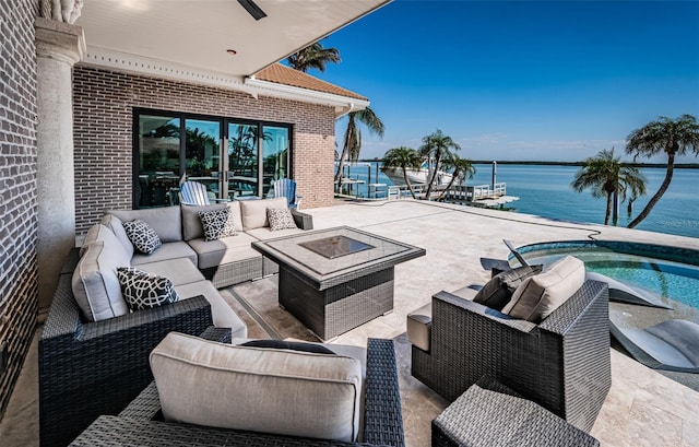 view of patio / terrace featuring a water view and an outdoor living space with a fire pit