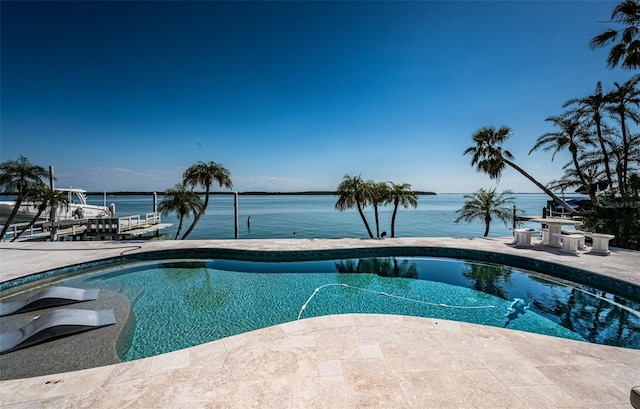 outdoor pool with a dock, a patio area, and a water view