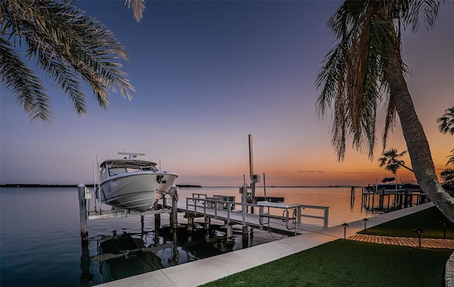 dock area with a water view, boat lift, and a yard