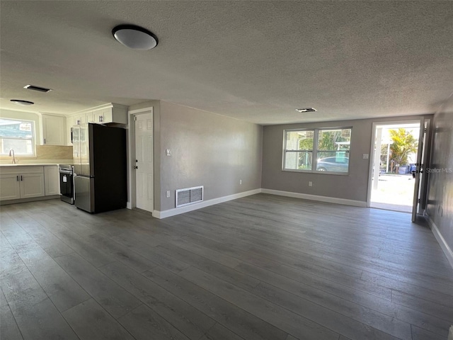 unfurnished living room with dark wood finished floors, a sink, visible vents, and baseboards