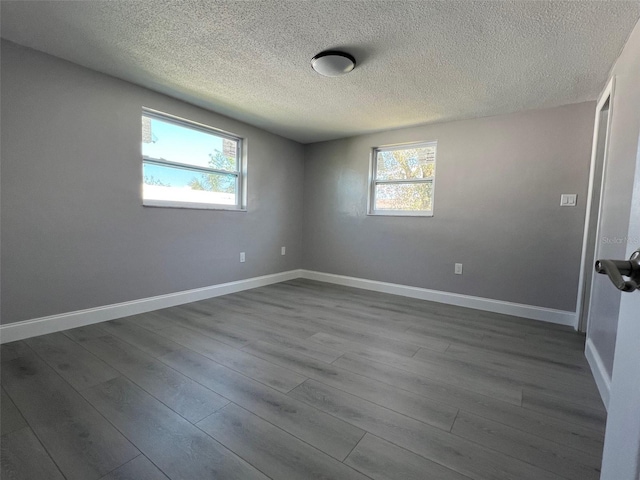 empty room with dark wood-style flooring, plenty of natural light, and baseboards