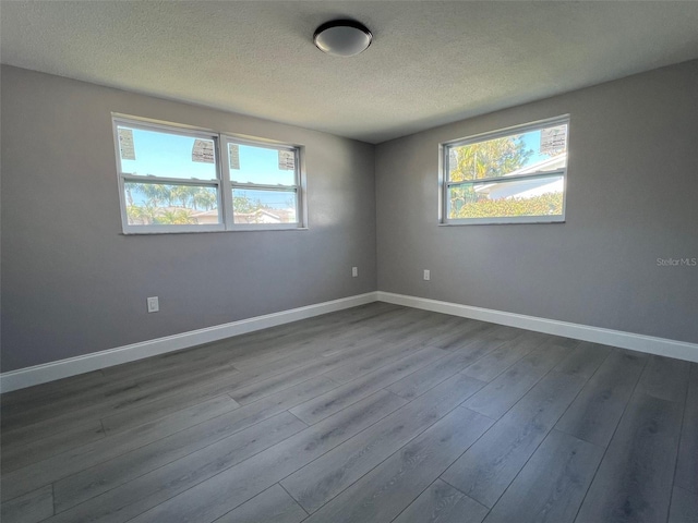 unfurnished room with dark wood-style floors, baseboards, and a textured ceiling