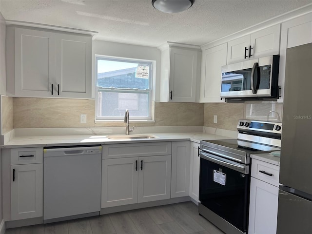 kitchen featuring appliances with stainless steel finishes, light countertops, a sink, and decorative backsplash