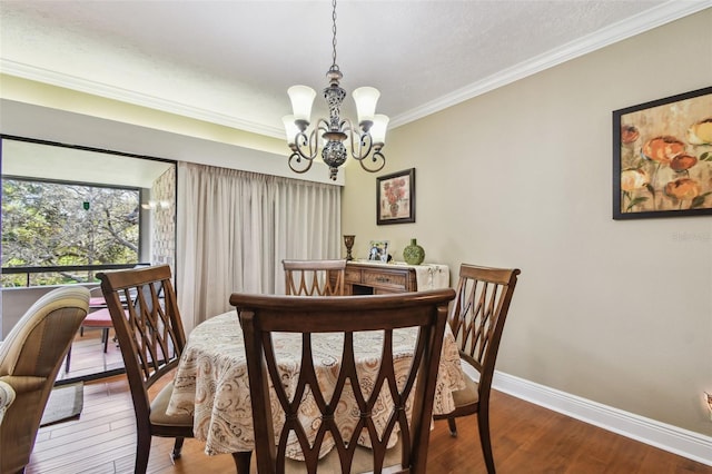 dining space featuring baseboards, ornamental molding, hardwood / wood-style flooring, and an inviting chandelier