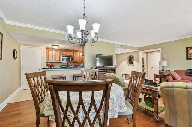 dining space featuring a textured ceiling, a notable chandelier, visible vents, and light wood-style floors