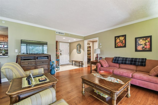 living room featuring a textured ceiling, hardwood / wood-style flooring, visible vents, baseboards, and crown molding