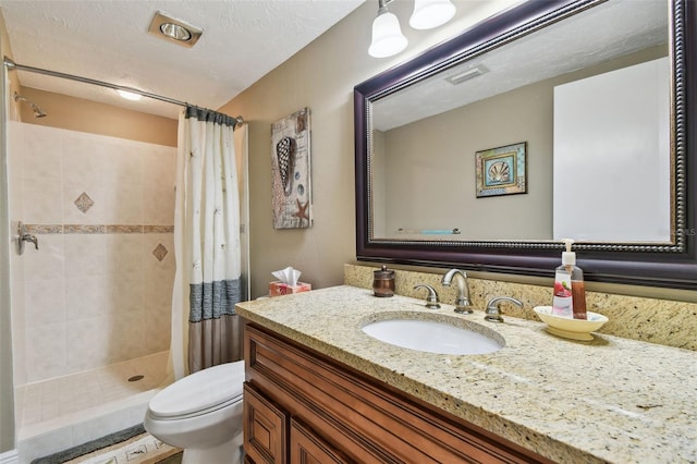 bathroom featuring a textured ceiling, toilet, visible vents, vanity, and a tile shower