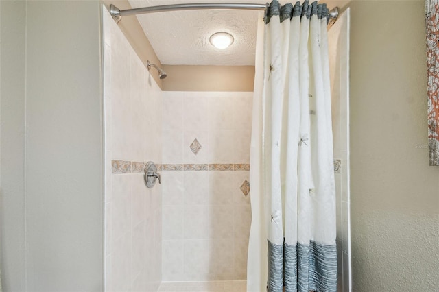 bathroom featuring a tile shower and a textured ceiling