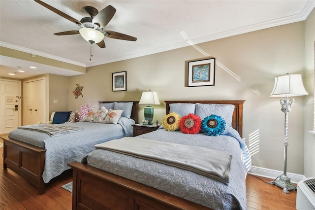 bedroom featuring ornamental molding, a ceiling fan, a textured ceiling, baseboards, and hardwood / wood-style flooring