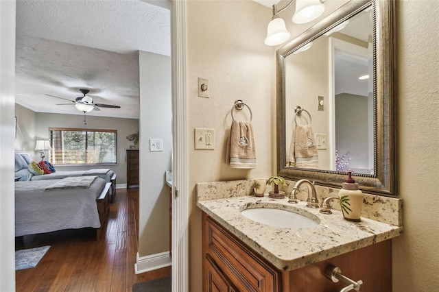 bathroom featuring a textured ceiling, ceiling fan, connected bathroom, hardwood / wood-style flooring, and vanity