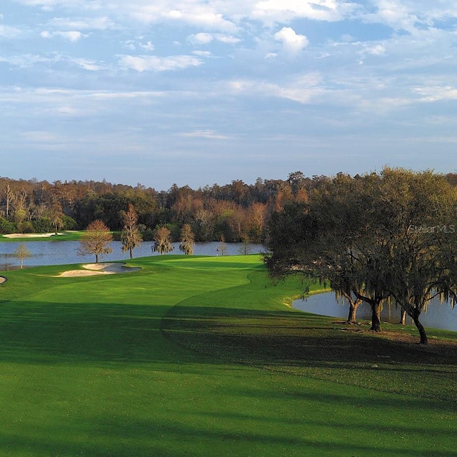 view of property's community featuring view of golf course, a lawn, and a water view