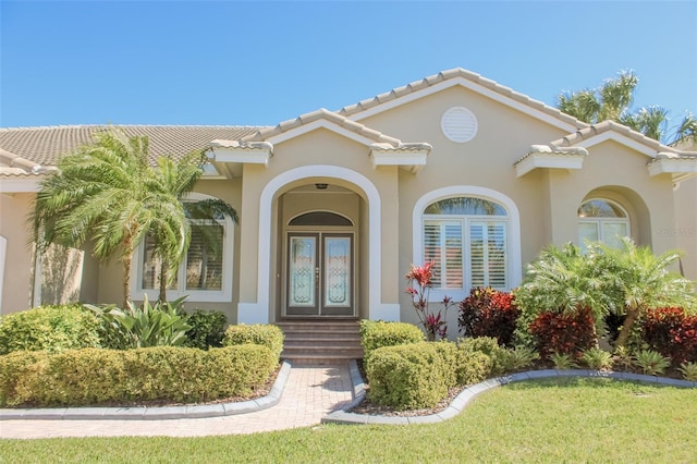 view of exterior entry featuring stucco siding, a tile roof, and french doors