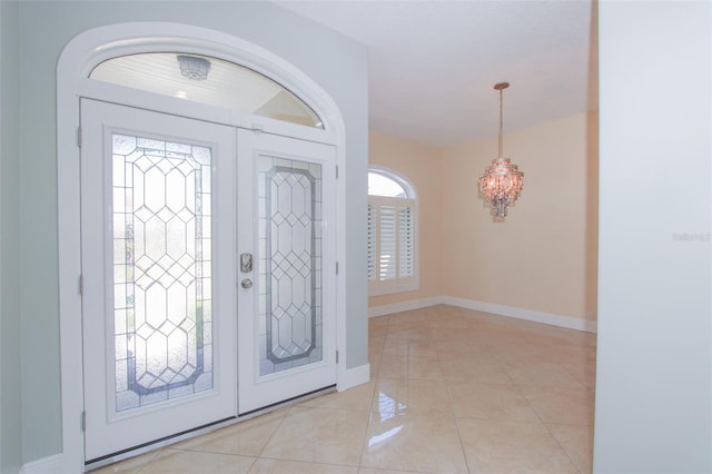 entryway with light tile patterned floors, baseboards, and an inviting chandelier