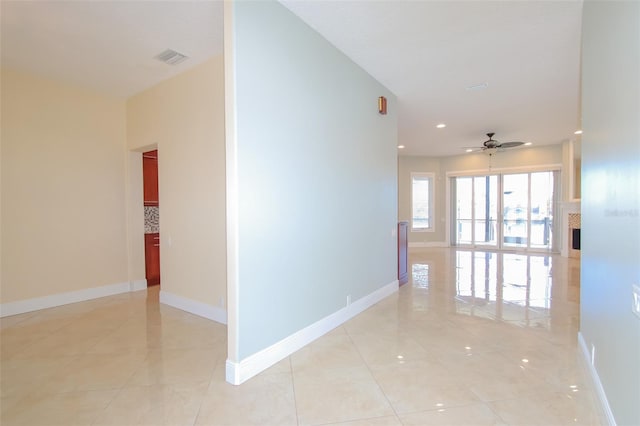 corridor featuring visible vents, baseboards, and light tile patterned floors