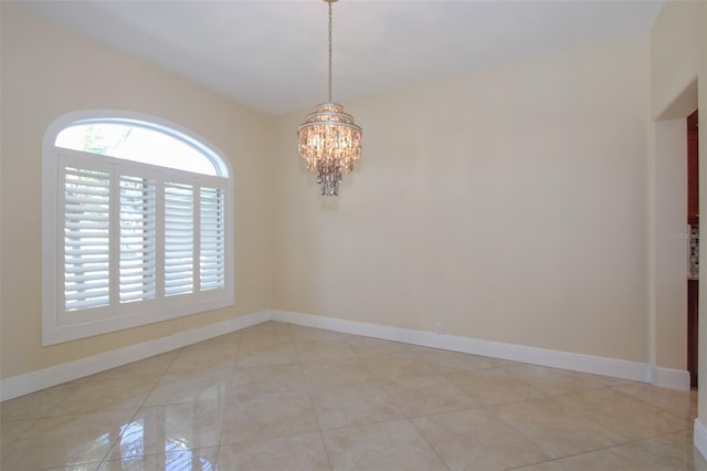 spare room with baseboards, a chandelier, and light tile patterned flooring