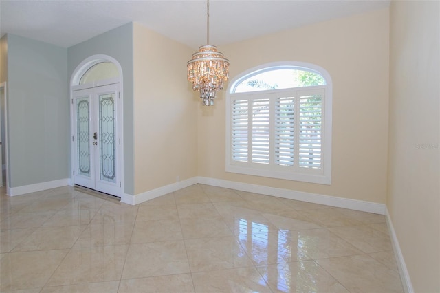 tiled entrance foyer featuring a notable chandelier, french doors, and baseboards