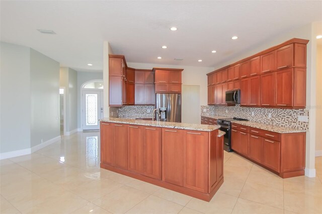 kitchen with light tile patterned floors, appliances with stainless steel finishes, light stone counters, a peninsula, and backsplash