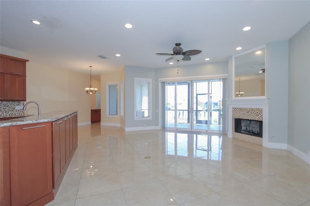 interior space with recessed lighting, baseboards, a tiled fireplace, and ceiling fan with notable chandelier