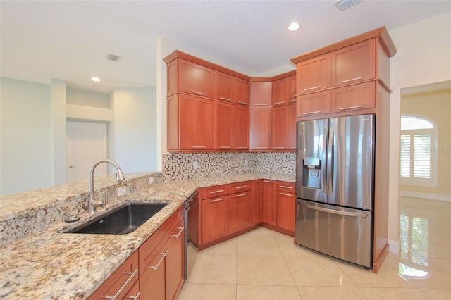 kitchen with light stone counters, tasteful backsplash, appliances with stainless steel finishes, light tile patterned flooring, and a sink