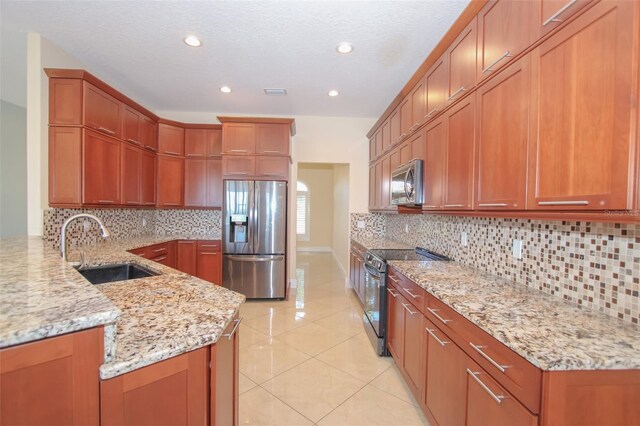 kitchen featuring light stone countertops, light tile patterned floors, appliances with stainless steel finishes, and a sink