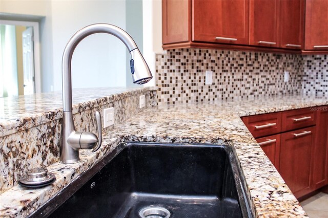 interior details with light stone counters, decorative backsplash, and a sink