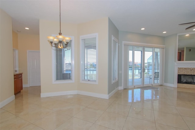 unfurnished dining area with a chandelier, recessed lighting, plenty of natural light, and a tiled fireplace