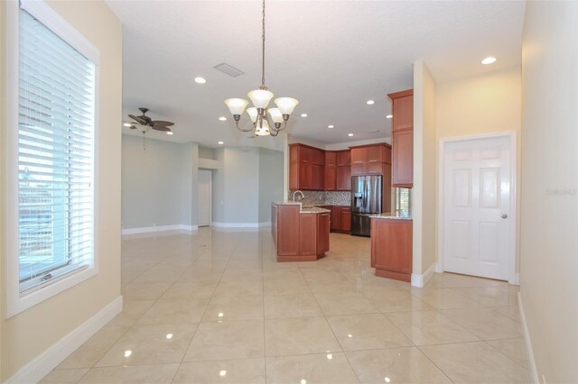 kitchen with stainless steel refrigerator with ice dispenser, light tile patterned floors, backsplash, open floor plan, and ceiling fan with notable chandelier