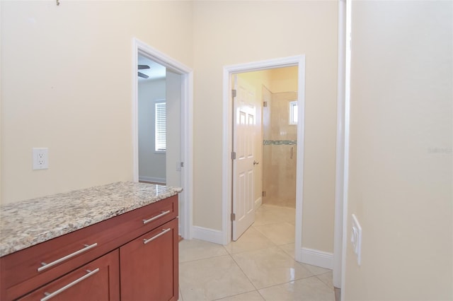 interior space with a stall shower, tile patterned flooring, vanity, and baseboards