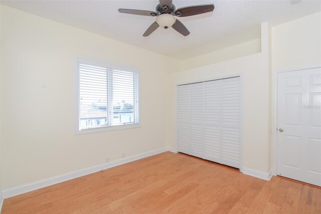 unfurnished bedroom with light wood-style floors, a ceiling fan, baseboards, and a closet