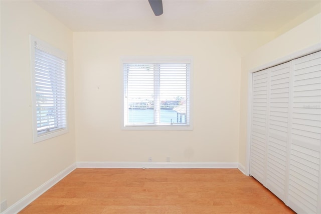 unfurnished bedroom featuring light wood-style floors, a closet, a ceiling fan, and baseboards