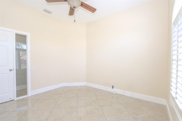 empty room with light tile patterned floors, baseboards, visible vents, and a ceiling fan