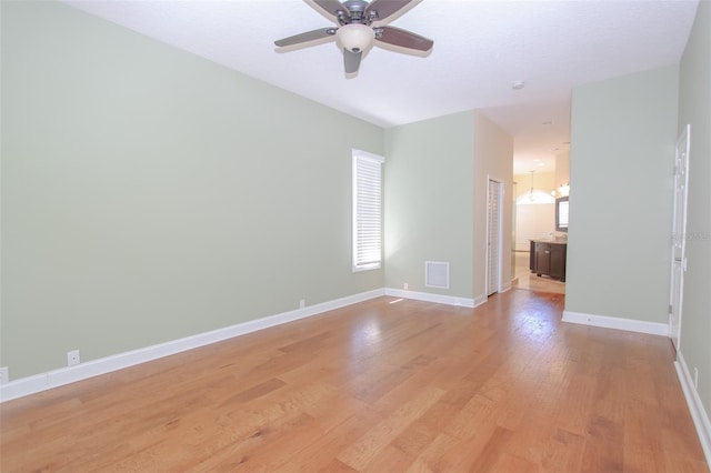 spare room with light wood-style floors, visible vents, baseboards, and ceiling fan