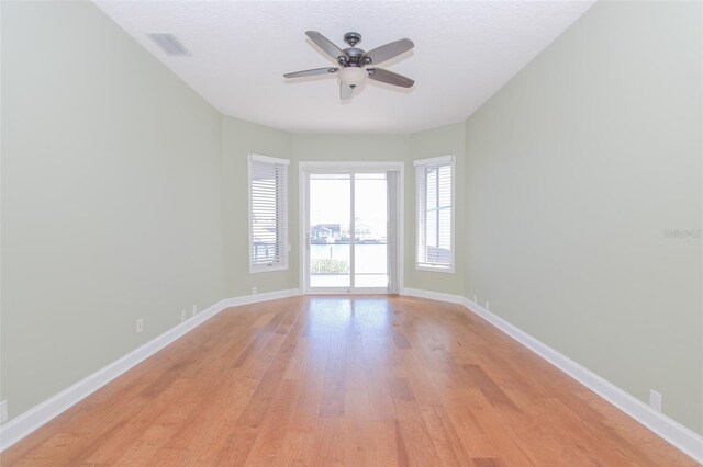 spare room featuring a ceiling fan, light wood-type flooring, visible vents, and baseboards