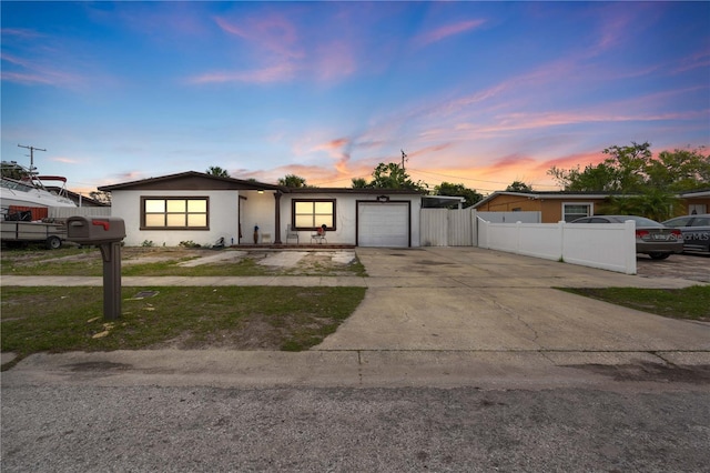 view of front of property with concrete driveway, an attached garage, fence, and stucco siding