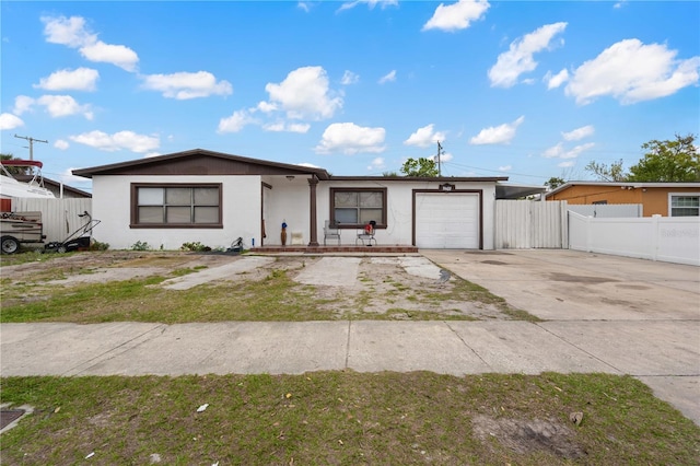 single story home featuring a garage, concrete driveway, fence, and stucco siding