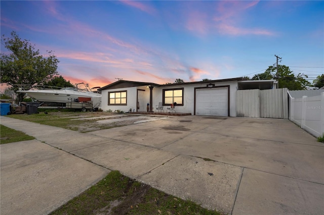 view of front facade featuring a garage, concrete driveway, fence, and stucco siding