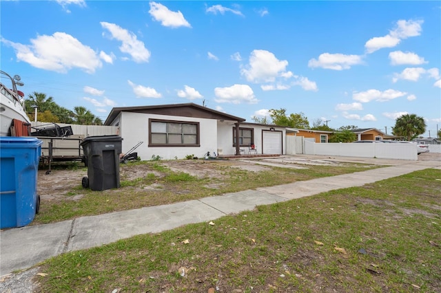 view of front of property featuring an attached garage, fence, and stucco siding