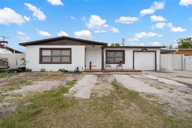 ranch-style home featuring concrete block siding, fence, driveway, and an attached garage