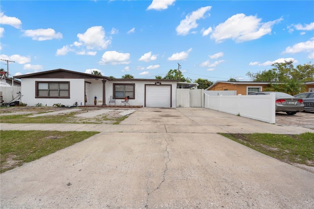 view of front of home with fence, driveway, an attached garage, and stucco siding