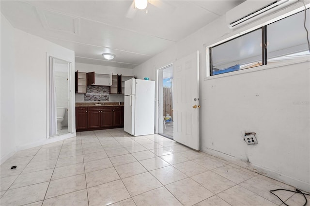 kitchen with an AC wall unit, light tile patterned flooring, a sink, and freestanding refrigerator