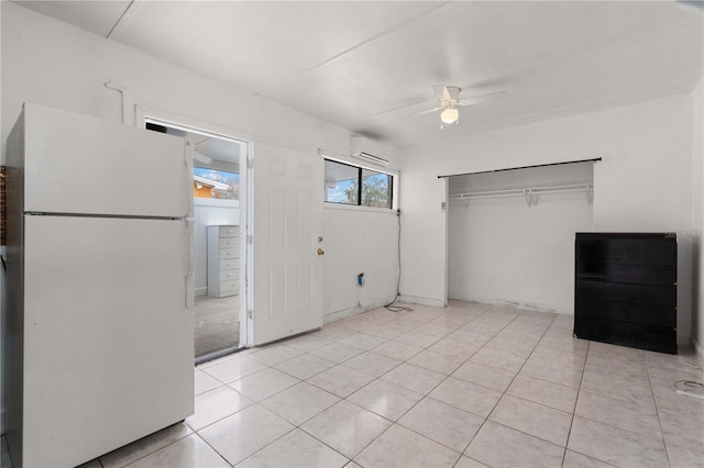 interior space featuring ceiling fan, light tile patterned flooring, a closet, a wall mounted AC, and freestanding refrigerator